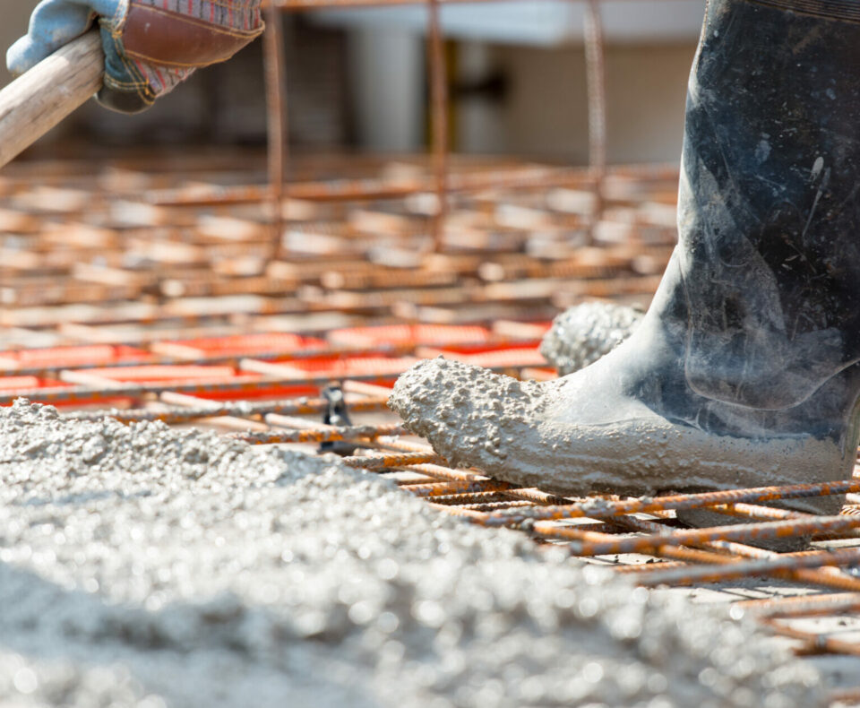 Worker pouring concrete mix at home foundation